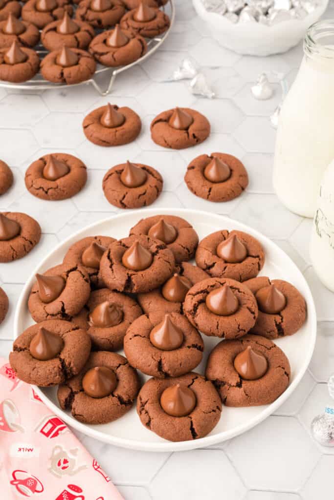 Chocolate Blossoms cookies on a white plate with bottles of milk in the background
