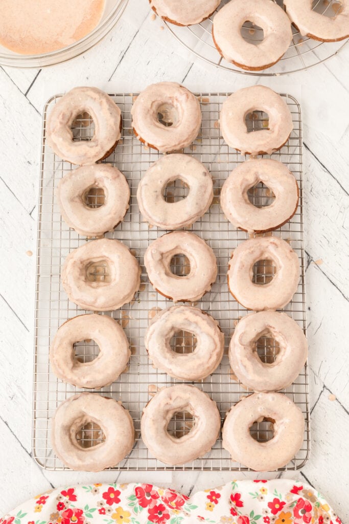 Glazed chocolate cinnamon doughnuts cooling on a wire rack.