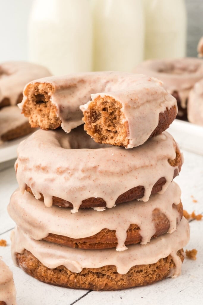 Close-up of a stack of glazed chocolate cinnamon doughnuts with a bite taken from the top one.