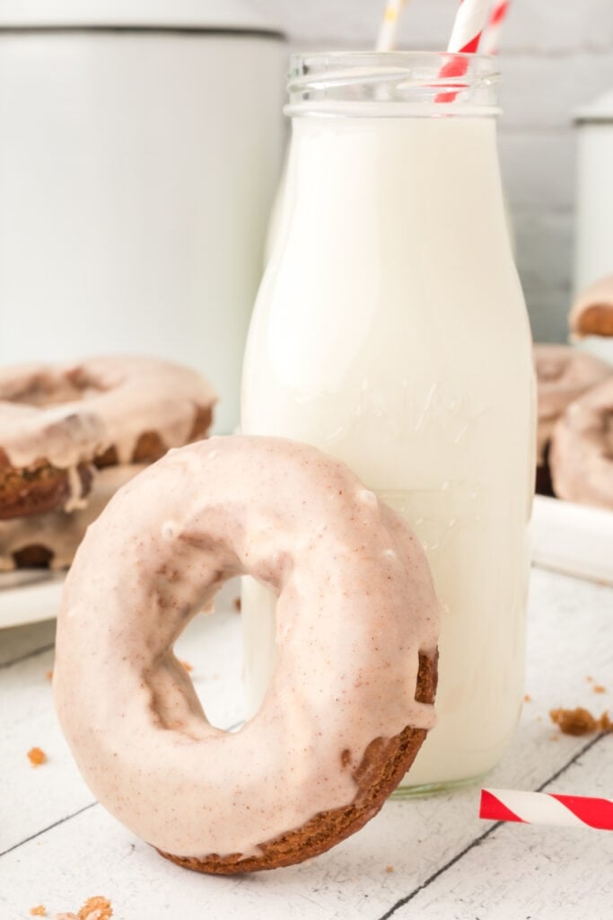 Glazed chocolate cinnamon doughnut in front of a milk bottle with a red-striped straw.