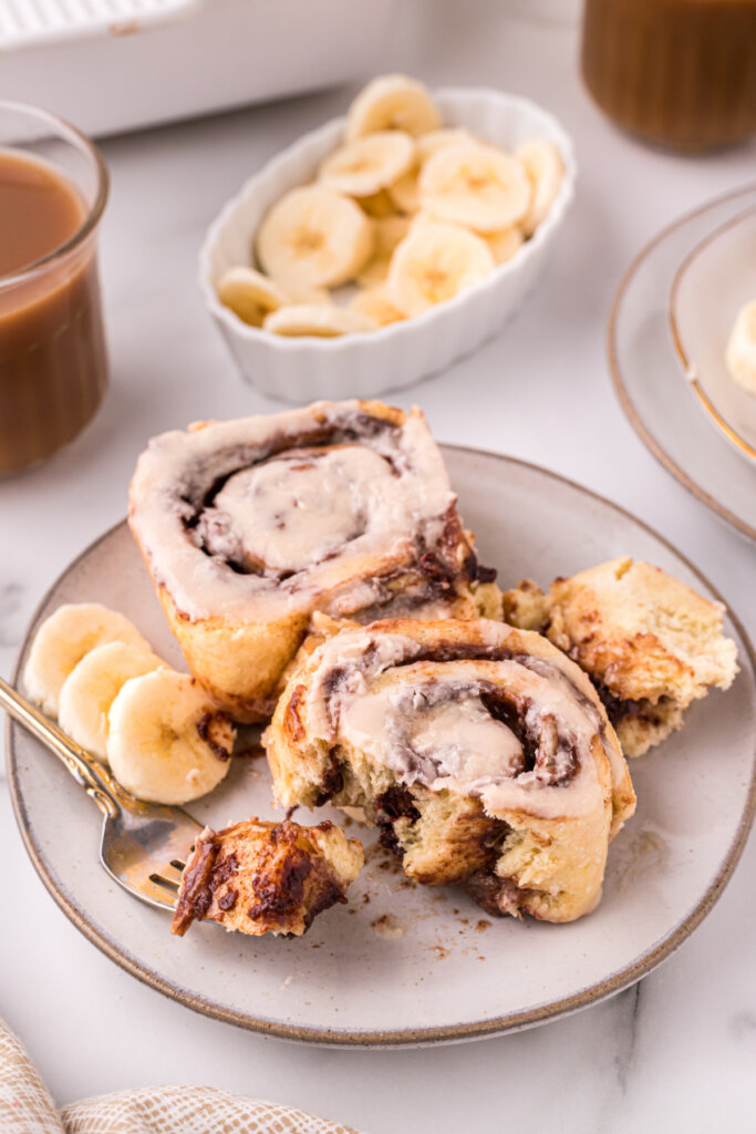 nutella banana cinnamon rolls on plate with banana slices and fork