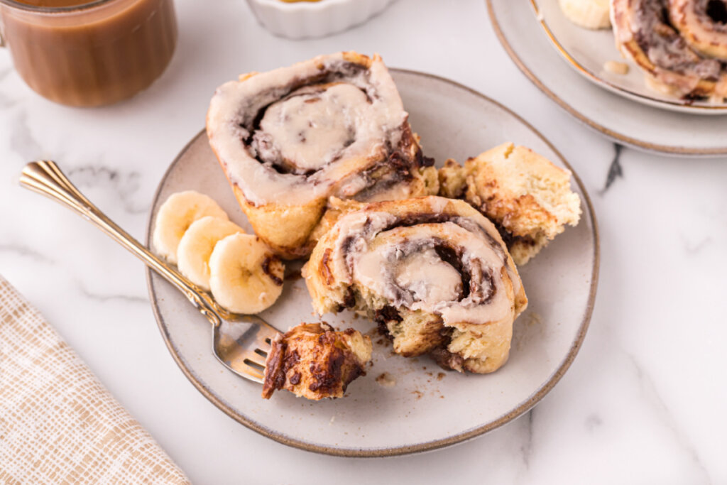 two nutella banana cinnamon rolls on plate with fork