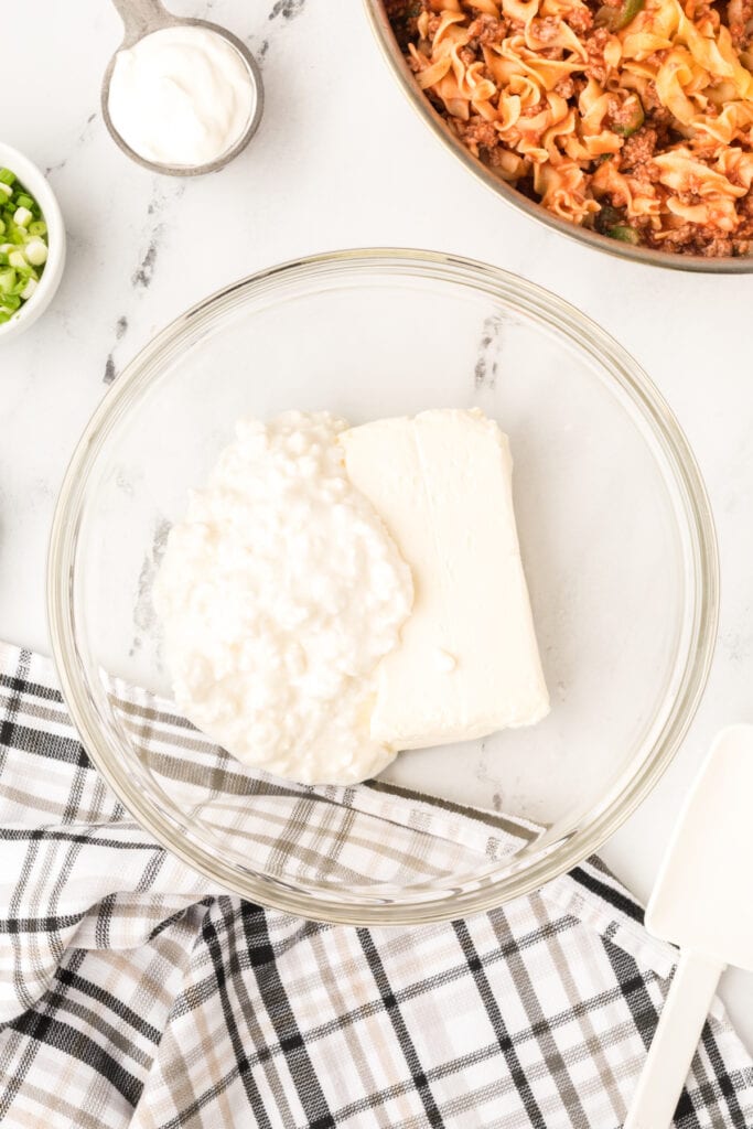 cottage cheese and cream cheese in a glass mixing bowl before blending