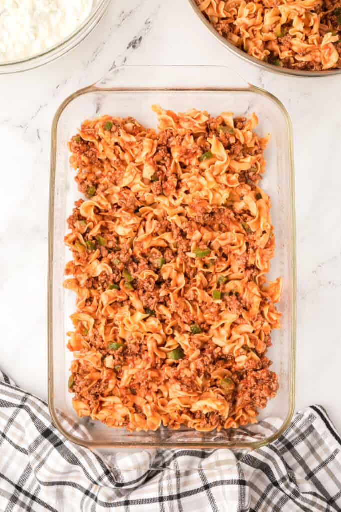 beef and noodle mixture spread into a glass baking dish