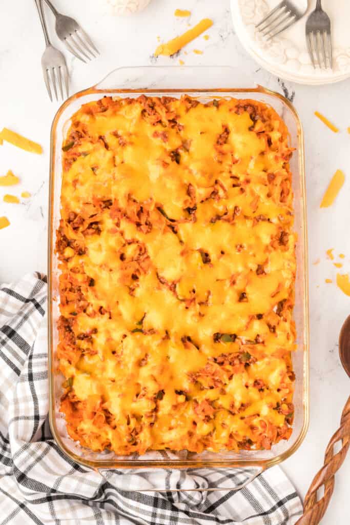 baked beefy sour cream noodle bake with melted cheddar cheese in a glass dish