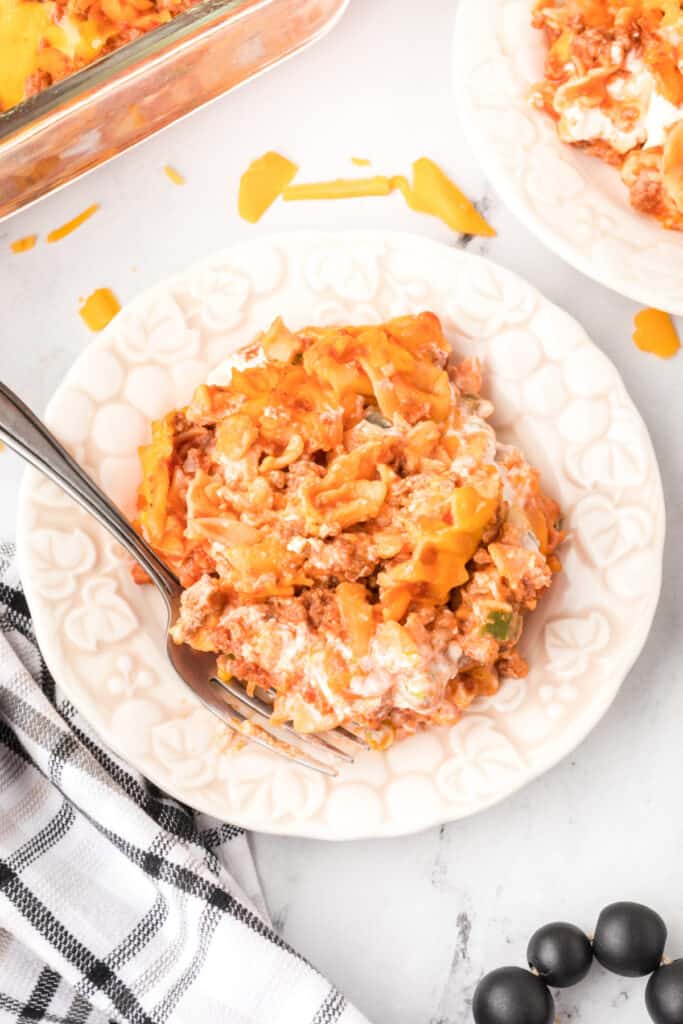 serving of beefy sour cream noodle bake on a plate with a fork on a black background