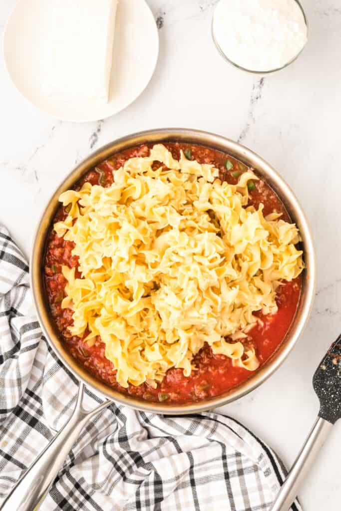 cooked egg noodles added to the beef and tomato sauce mixture in skillet