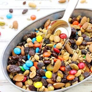Sweet & Salty Trail Mix in a bowl with a scoop. Loose pieces are spilled around the bowl.