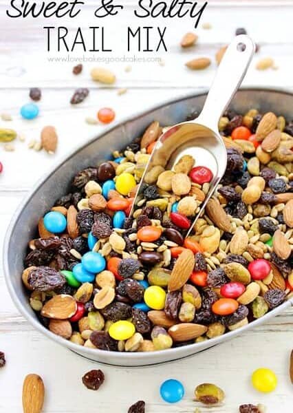 Sweet & Salty Trail Mix in a bowl with a scoop. Loose pieces are spilled around the bowl.
