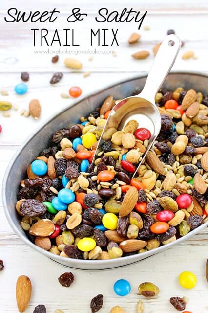 Sweet & Salty Trail Mix in a bowl with a scoop. Loose pieces are spilled around the bowl.