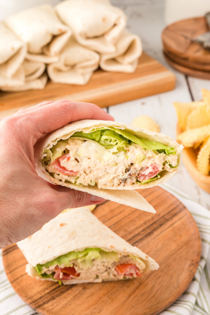 hand holding a blt avocado chicken salad wrap