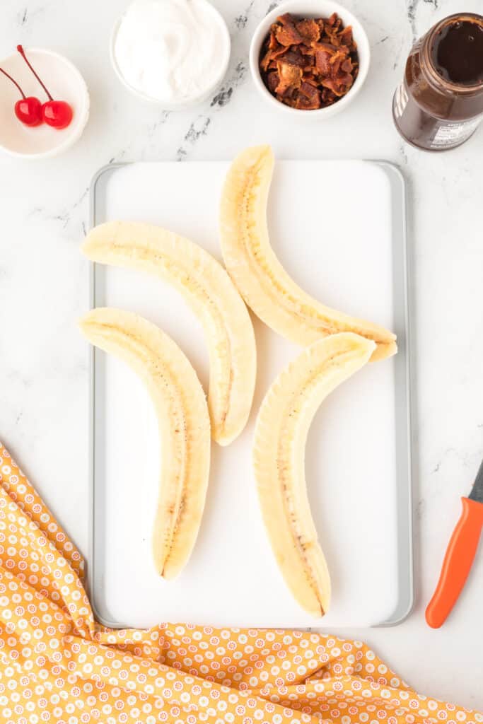 Bananas split lengthwise on a cutting board for assembling an Elvis Banana Split.