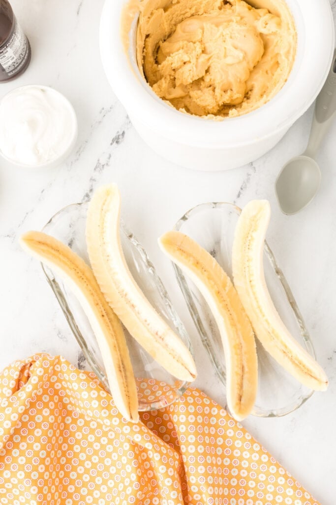 Banana halves arranged in banana split dishes with homemade peanut butter ice cream ready for assembly.