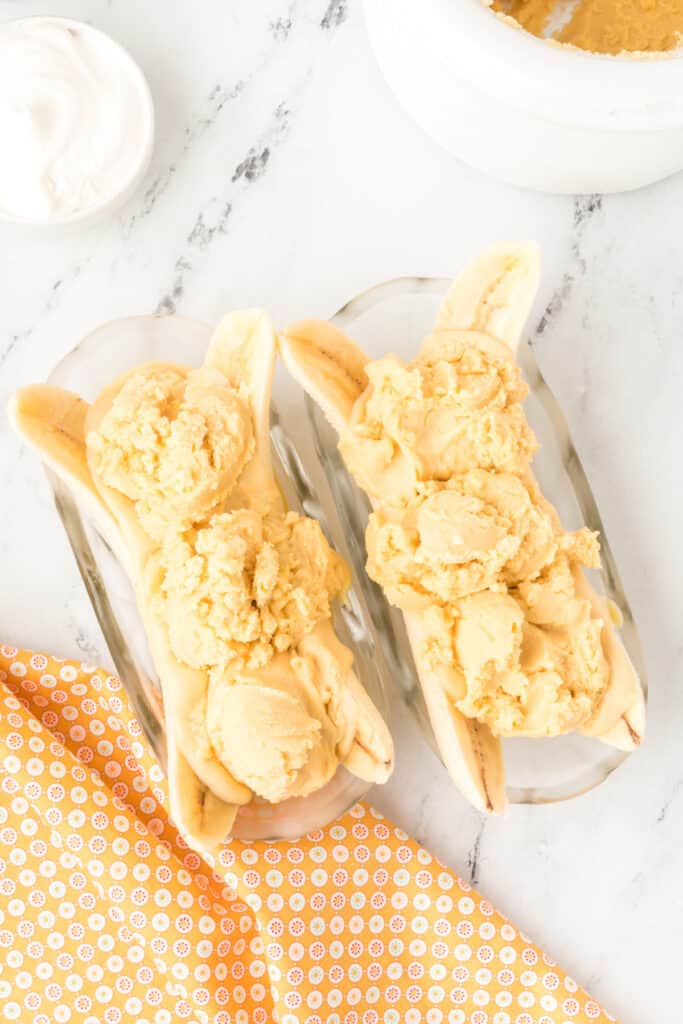 Homemade peanut butter ice cream scooped onto banana halves for an Elvis Banana Split.