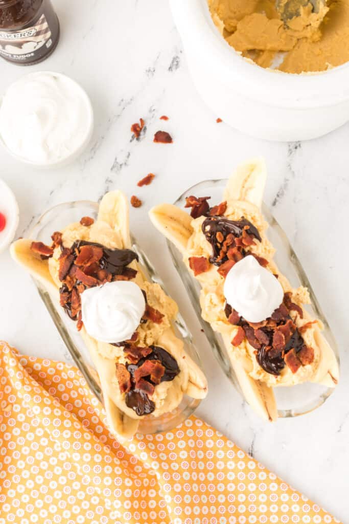 Whipped cream added to homemade peanut butter ice cream, hot fudge, and bacon on an Elvis Banana Split.