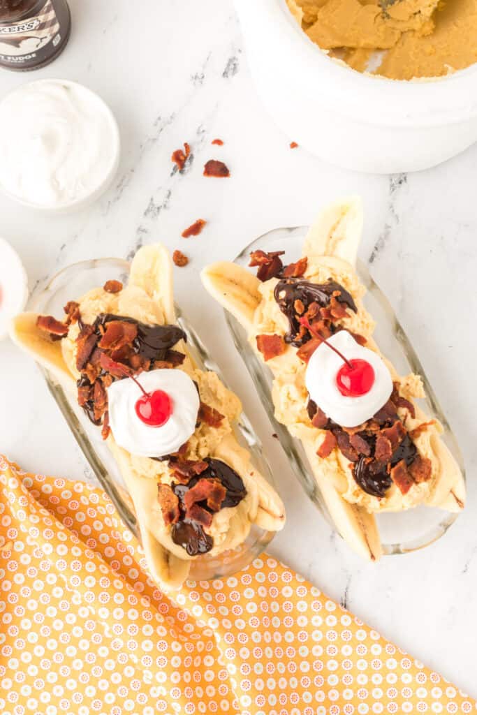 Maraschino cherries placed on top of whipped cream to finish an Elvis Banana Split.