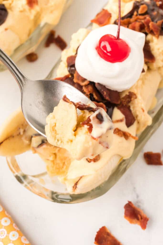 Elvis Banana Split made with homemade peanut butter ice cream, sliced banana, hot fudge sauce, crispy bacon, whipped cream, and a maraschino cherry.