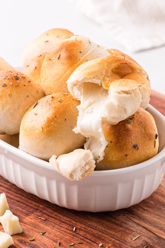 garlic herb cheese bombs in white serving platter with the top bomb showing the cheese oozing