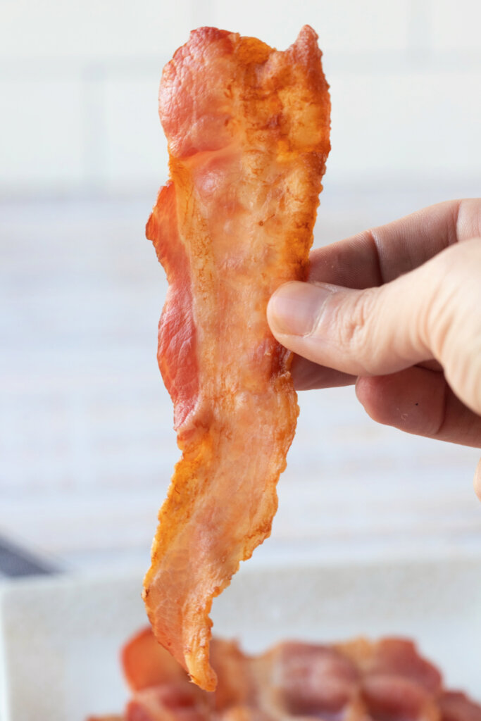 hand holding a slice of bacon