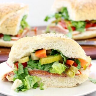 Italian sub sandwich on a white plate, cut in half.