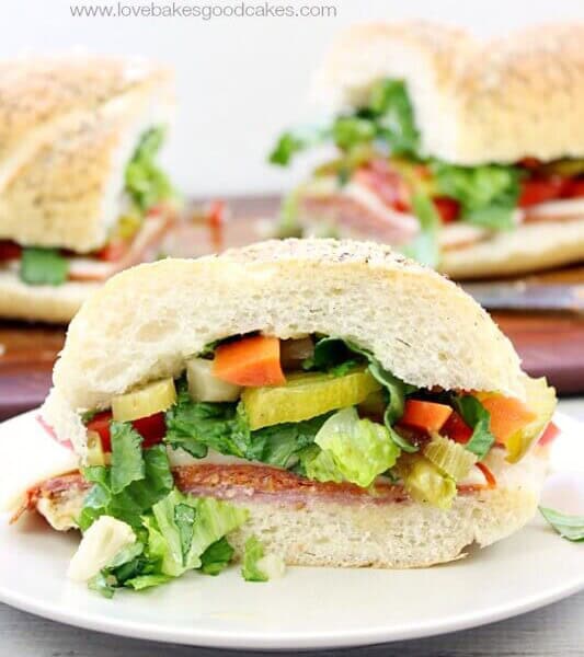 Italian sub sandwich on a white plate, cut in half.