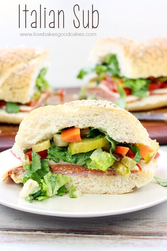 Italian sub sandwich on a white plate, cut in half.