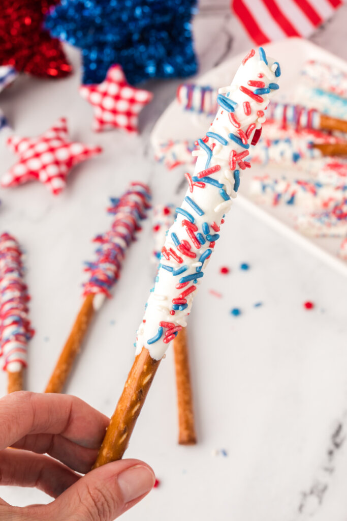 hand holding decorated chocolate dipped pretzel rod