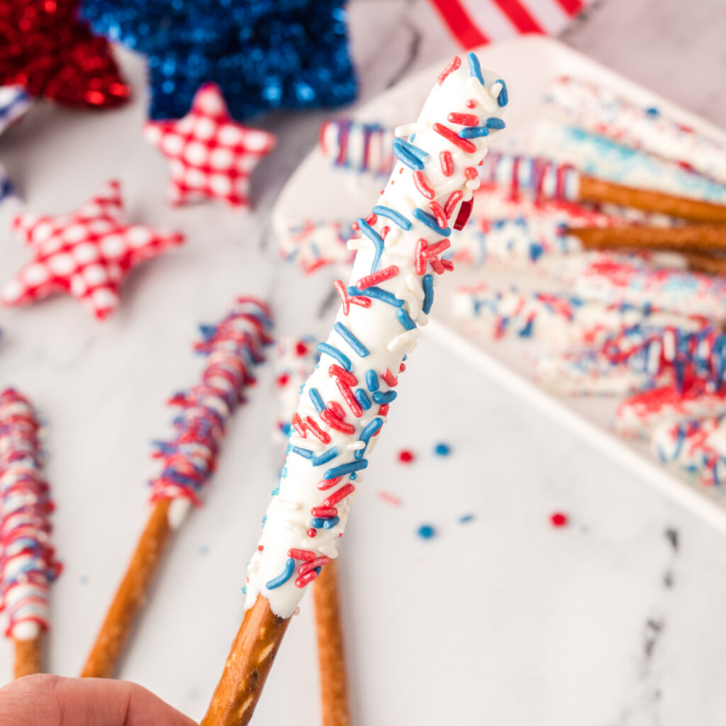 hand holding chocolate covered pretzel rods