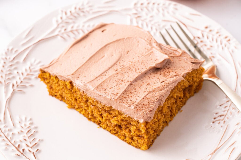 Close-up of a single pumpkin bar topped with Nutella frosting on a decorative plate with a fork.