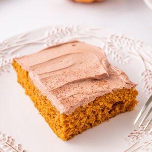 Square close-up of a pumpkin bar topped with Nutella buttercream on a white plate.