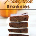 Pumpkin Brownies stacked up with parchment paper.