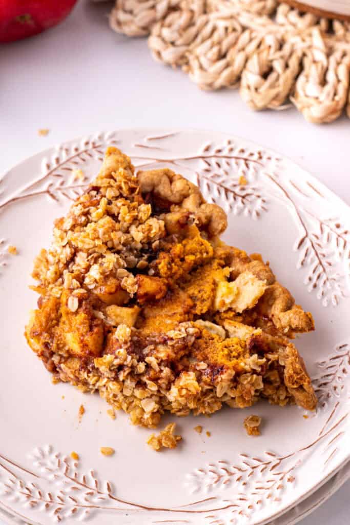 Slice of Pumpkin Pie Apple Crisp served on a decorative plate showing layers of pumpkin, apple, and oat crumble.