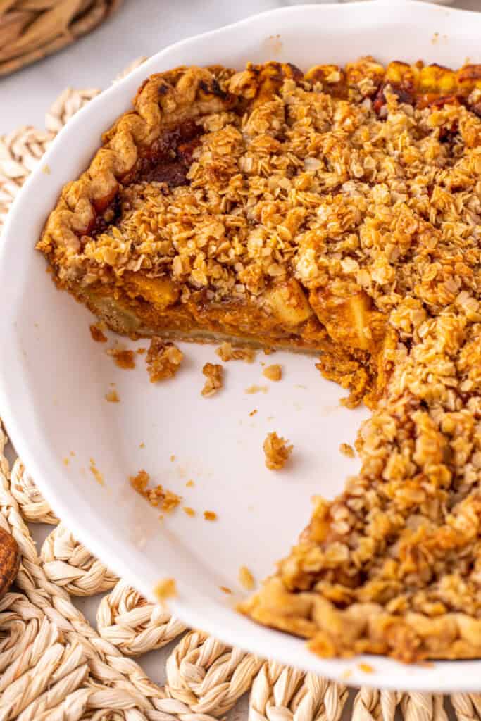 Close up of a baked Pumpkin Pie Apple Crisp with a slice removed, showing the pumpkin and apple layers under the oat crumble.
