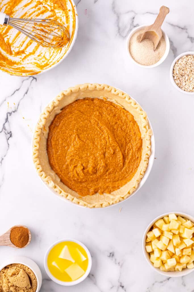 Pumpkin filling spread evenly inside an unbaked pie crust before baking.
