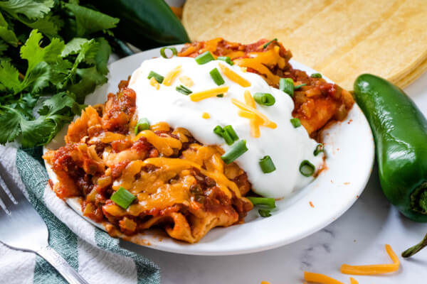 ground beef enchiladas topped with sour cream on plate