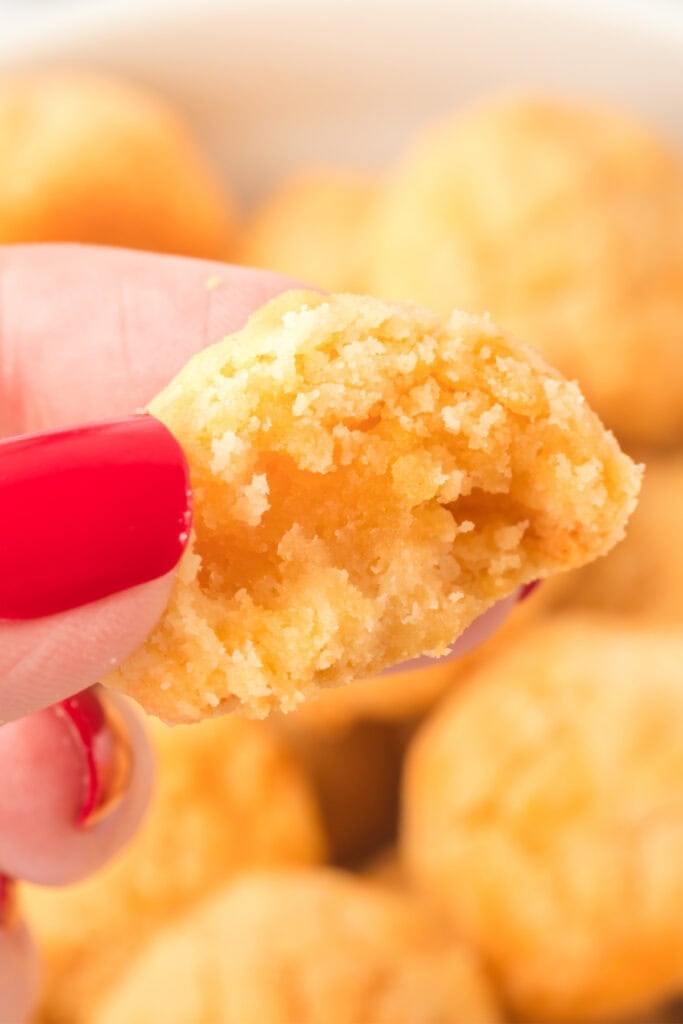 Close-up of a homemade cheese bite showing the soft cheesy center and crumbly texture
