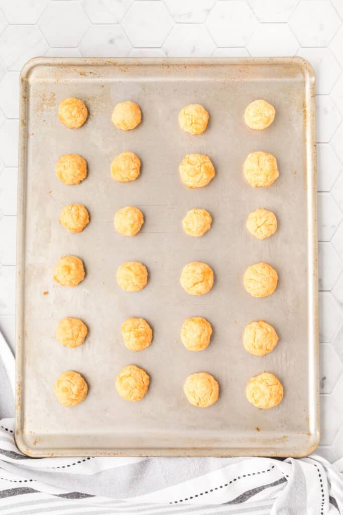 Freshly baked cheese bites on a baking sheet with a golden brown crust