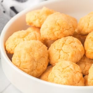 Square image of homemade cheese bites in a bowl with a golden buttery texture perfect for parties and snacks