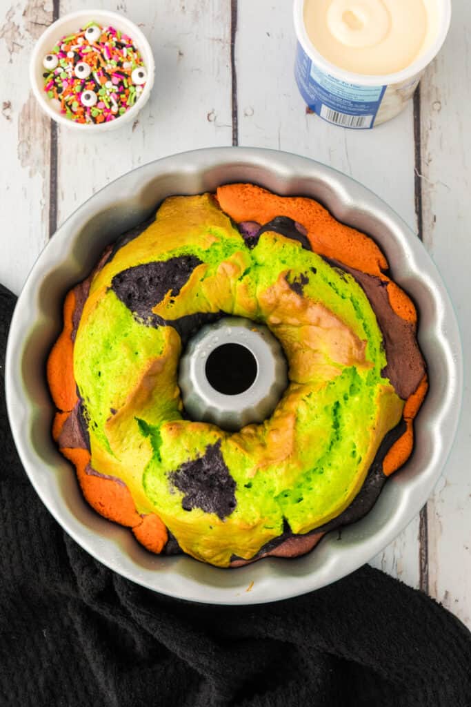Freshly baked Halloween Bundt Cake in the pan showing vibrant orange, green, and black layers.