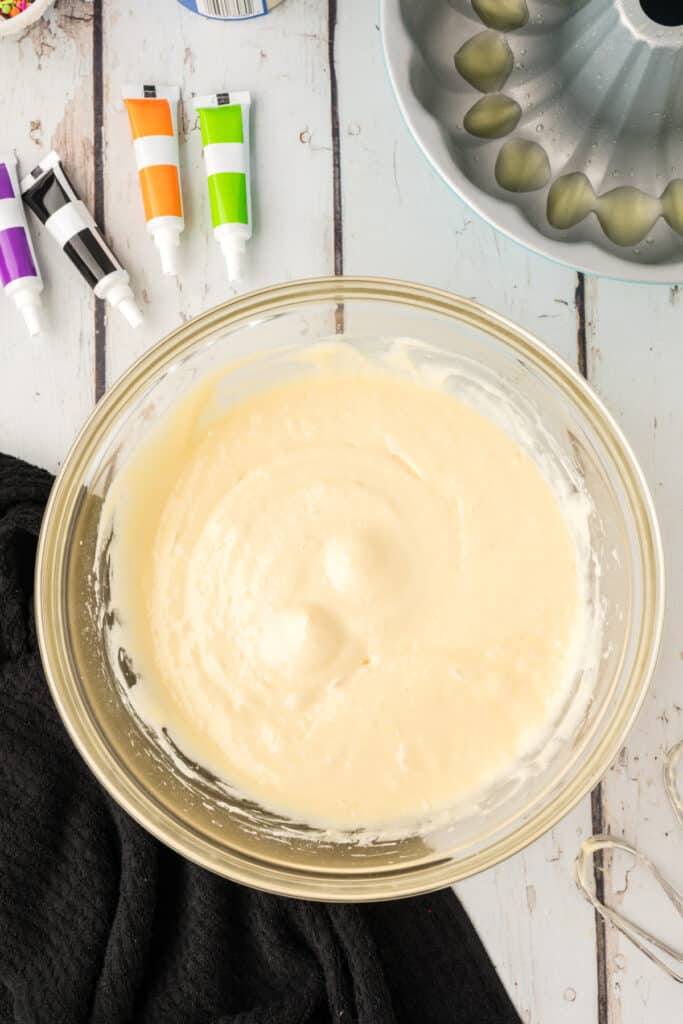 Mixing bowl filled with white cake batter ready to be divided and tinted with Halloween food coloring.