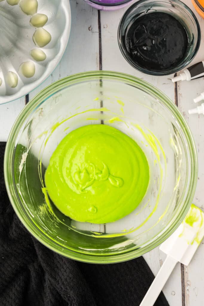 Bowl of neon green cake batter with a spatula beside it, ready for layering in the bundt pan.