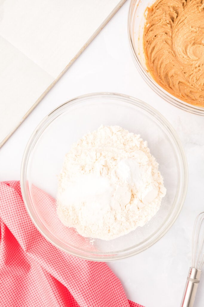 dry ingredients including flour, baking soda, and salt in a glass mixing bowl on a white surface
