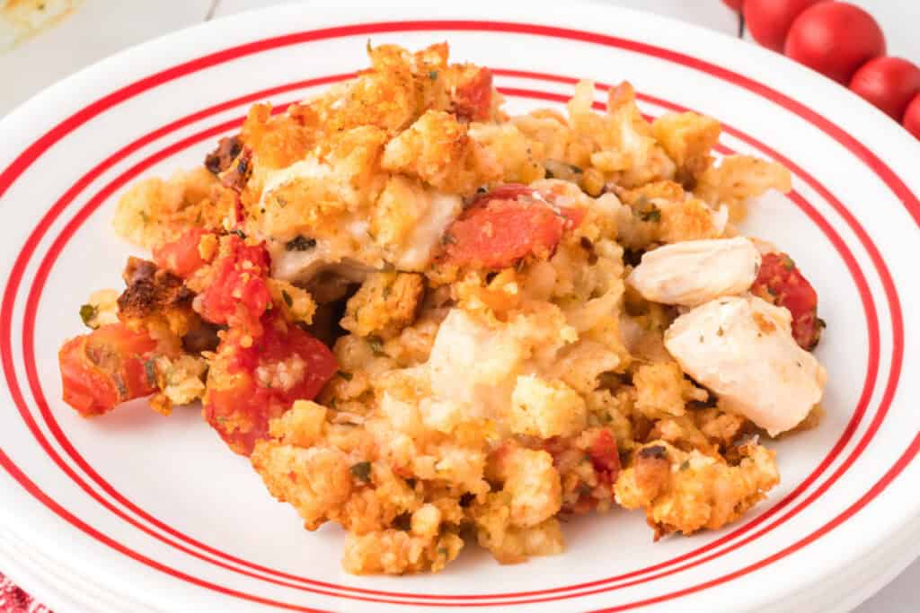 Serving of Chicken Bruschetta Bake on a white plate with chicken, tomatoes, melted mozzarella cheese, and stuffing topping.