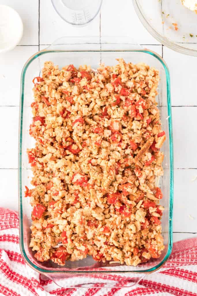 Chicken Bruschetta Bake assembled in a baking dish with the tomato stuffing mixture spread over the top before baking.