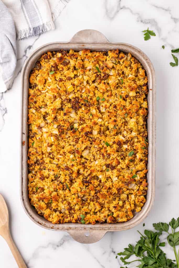 Overhead view of baked cornbread dressing with a golden brown top inside a metal baking dish.