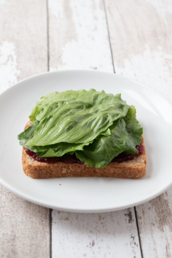 adding lettuce to sandwich