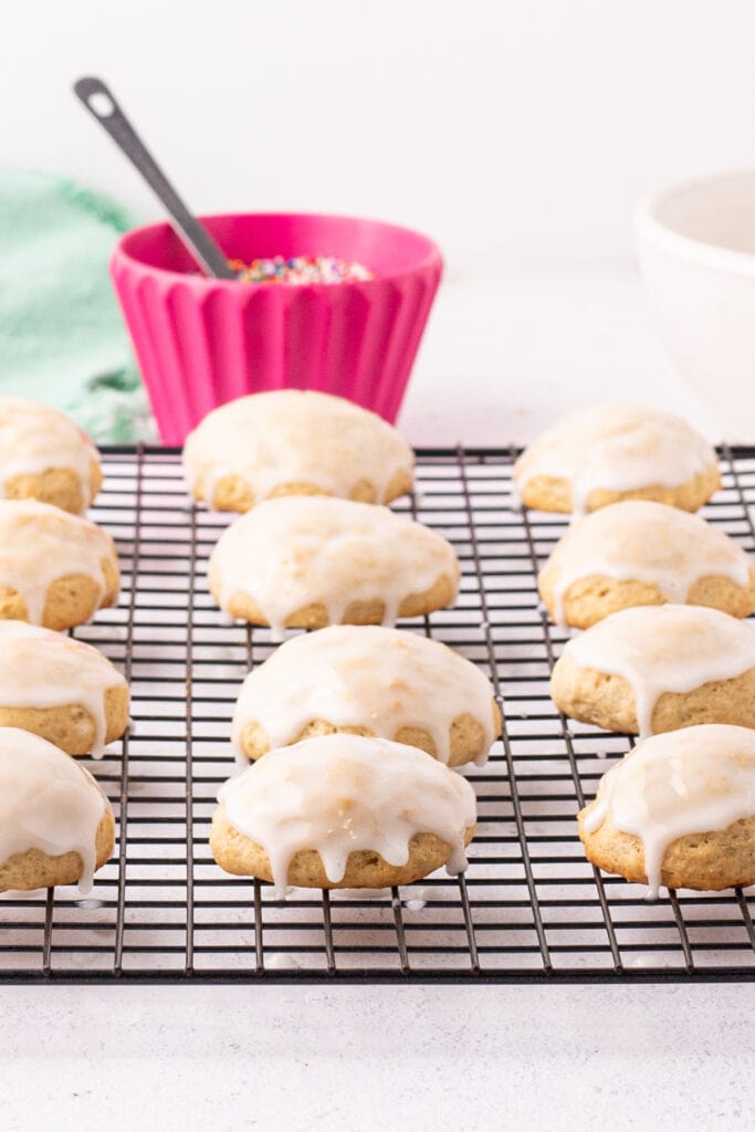 Glazed ricotta cookies setting on a cooling rack, ready for sprinkles