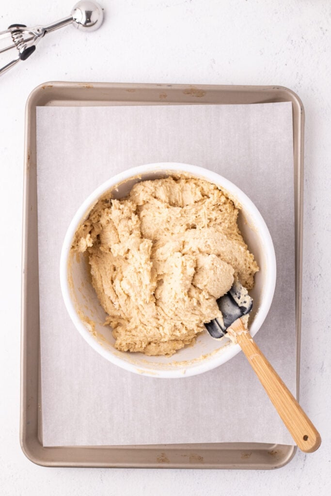 Finished cookie dough in a mixing bowl with spatula ready to scoop