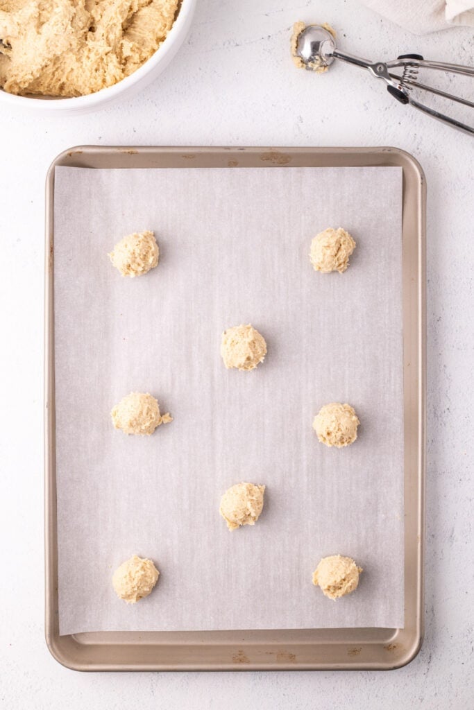 Scooped dough balls spaced on a parchment-lined baking sheet