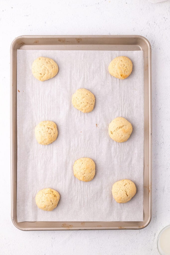 Baked ricotta cookies cooling on a parchment-lined tray